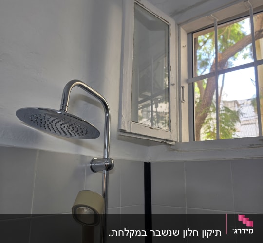 חלון זכוכית בחדר רחצה מעל ראש מקלחת